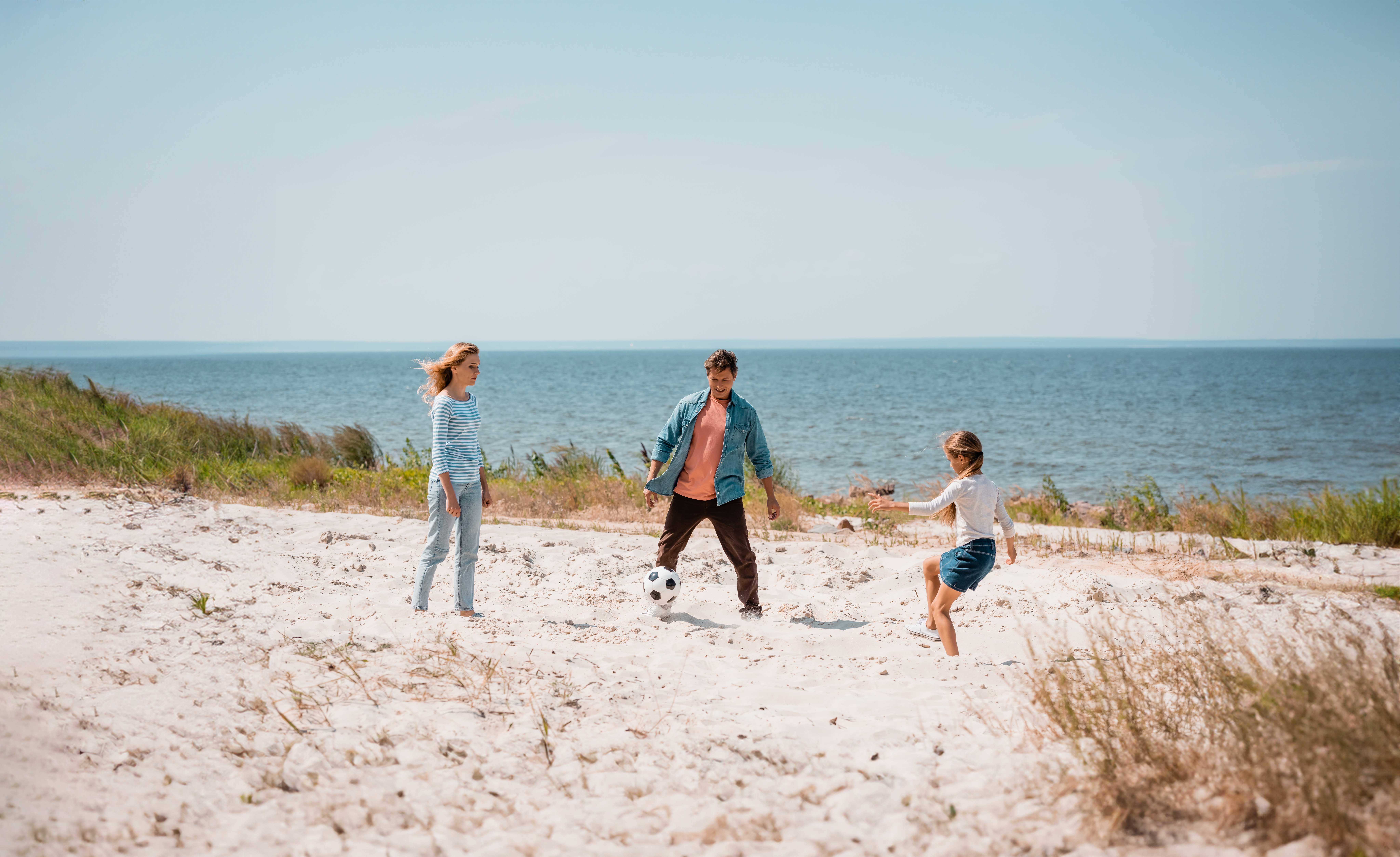 a family playing soccer on the beach